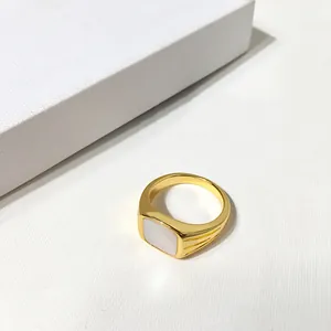 Gros plan d'une bague chevalière dorée avec incrustation en nacre et rainures latérales