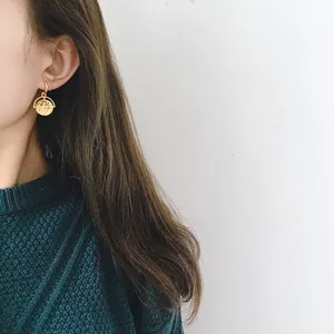 Vintage gold Roman coin drop earrings worn by a model in a dark green sweater