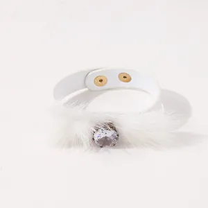Detail van witte PU-lederen armband met pluche bont en grote sprankelende diamantgesp