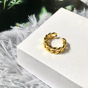 Detailed view of a gold chain link ring on a white jewelry stand with green accents