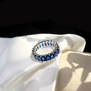 Macro shot of silver ring with full circle rectangular blue zircon stones on white silk