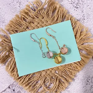 Elegante lange ketting oorbellen met metalen ballen in goud en zilver op blauwe kaart