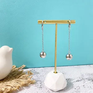 Minimalistische lange metalen kettingoorbellen met zilveren bollen op een standaard
