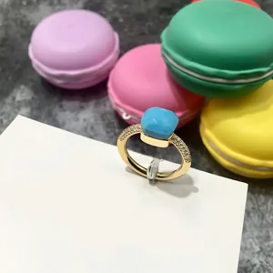 Detalle de anillo dorado con gema azul facetada y pavé de circonitas cúbicas brillantes