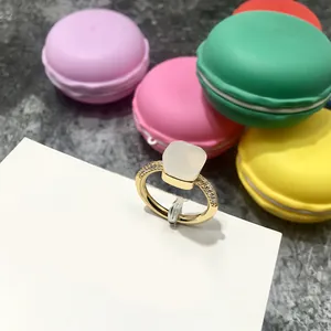 Primer plano de anillo dorado con gema cuadrada traslúcida y pavé de diamantes