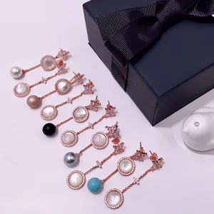 Detailed macro view of asymmetric rose gold star earrings with mother of pearl and multi-color pearls