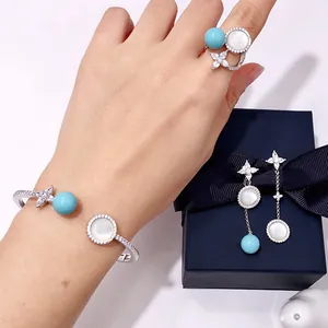 Detail of silver jewelry set featuring blue beads and white shell floral patterns