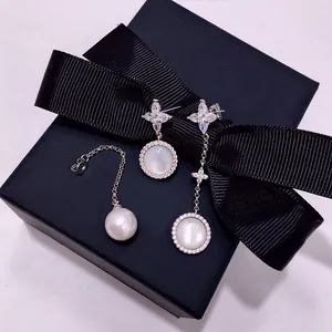 Asymmetric star earrings with natural shell pearl and marquise zircon on a black gift box