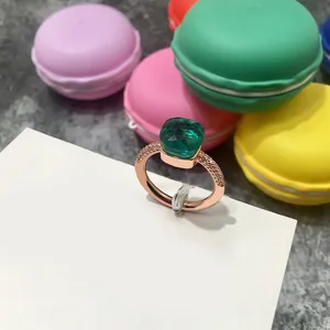 Anillo de cristal verde talla cojín en oro rosa con pavé de diamantes sobre fondo colorido