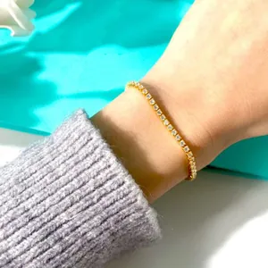 Detailaufnahme eines funkelnden 2mm Gold Tennisarmbands mit Zirkonia-Steinen am Handgelenk