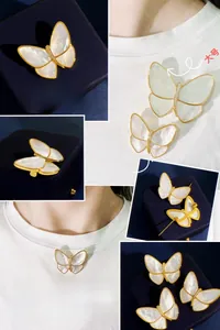 Detail view of large and small white shell butterfly brooches with gold plating