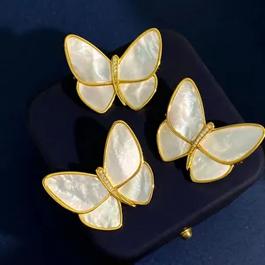 Elegant gold butterfly brooch with white shell inlay and diamond accents on velvet