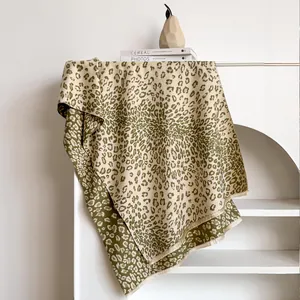Écharpe à imprimé léopard olive et beige avec de douces franges sur un support d'exposition