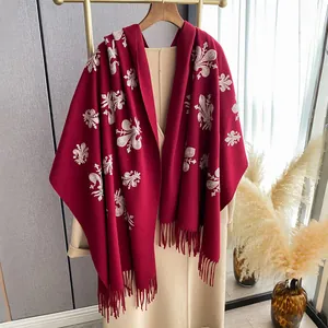 Detalle de chal rojo estilo cachemir con bordado floral blanco y remate de flecos