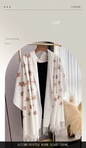 Close-up of white cashmere-like scarf featuring elegant bee embroidery and tassel details