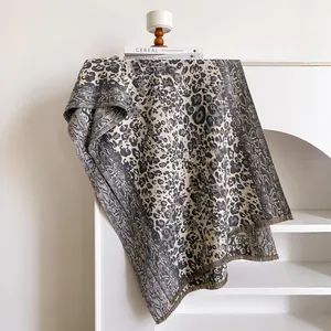 Détail de l'écharpe à motif léopard avec franges sur une étagère blanche minimaliste