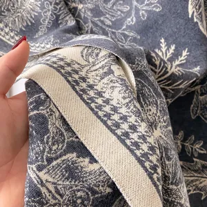 Detail of cashmere scarf showing blue Toile de Jouy tropical plant jacquard pattern