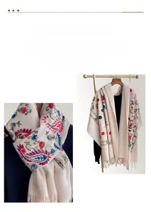 Detail of floral embroidery and paisley patterns on thick beige pashmina shawl with tassels