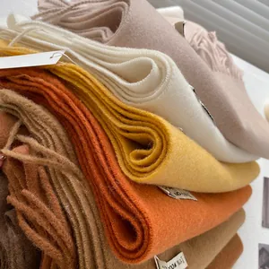 Detail of multi-color 100% wool scarves with long tassels showing soft texture and layering