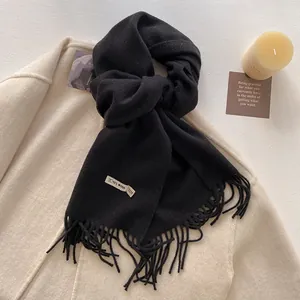 Detail of premium black wool scarf featuring 100% wool label and classic fringe edges