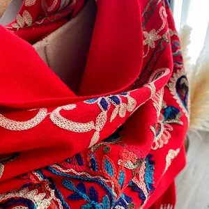 Macro detail of high-quality floral embroidery on a thick red winter shawl wrap