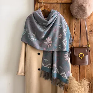 Detail of grey cashmere-like scarf with pink flowers, blue patterns and tassels on a coat