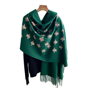 Dark green cashmere-feel scarf with golden bee embroidery and fringed edges on hanger