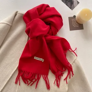 Detailed view of dark red wool blend scarf with fringe on light beige winter coat