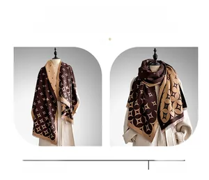 Dettaglio della sciarpa con motivo geometrico in finto cashmere e nappe marroni