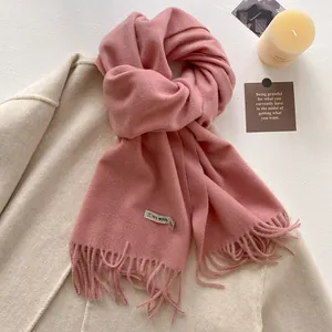 Detail of pink wool blend scarf with fringe edges and label on a beige coat