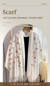 Dettaglio di sciarpa bianca in finto cashmere con ricami a cuore marroni e frange
