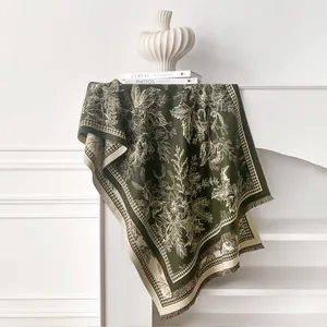 Detailed view of dark green cashmere scarf with vintage floral patterns and tassels
