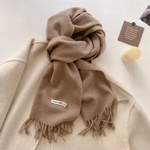 Detail of a thick brown tassel scarf on a beige coat with a 10% wool content label