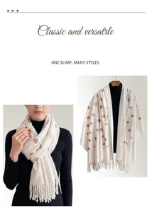 Dettaglio della sciarpa pashmina bianca con motivi a cuore marroni e frange classiche