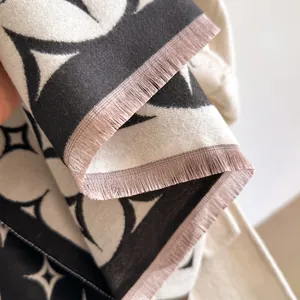 Dettaglio dello scialle in finto cashmere con motivi a stelle bianco-neri e frange rosa
