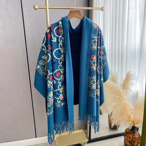 Close-up of ethnic floral embroidery and tassel fringe on a thick navy blue winter shawl