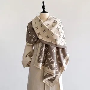 Dettaglio sciarpa a motivi geometrici con frange su un manichino in cappotto