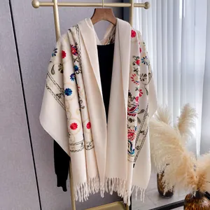 Detail of cream floral embroidery and fringe tassels on a thick ethnic winter shawl