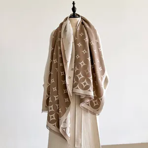 Dettaglio di una morbida sciarpa con motivo geometrico a stelle e frange in beige e marrone