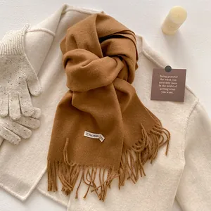 Detail of soft wool blend scarf in camel brown color with classic fringe edges and warm texture