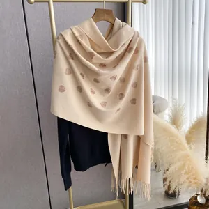 Dettaglio sciarpa beige effetto cashmere con cuori ricamati caffè scuro e nappine