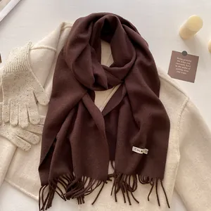 Detail of dark brown wool scarf with tassels paired with gloves and winter accessories