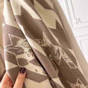 Detailed close-up of soft houndstooth knit scarf texture in beige and brown tones