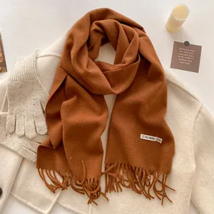 Close-up of caramel cashmere-like scarf with fringe detail and 10% wool label