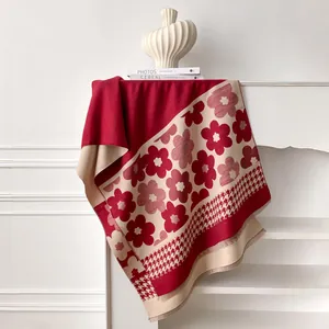 Close-up of a thick winter scarf with floral and houndstooth patterns and fringe edges