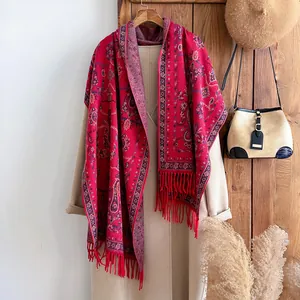 Châle rouge à motifs paisley en imitation cachemire avec pompons sur un manteau d'hiver