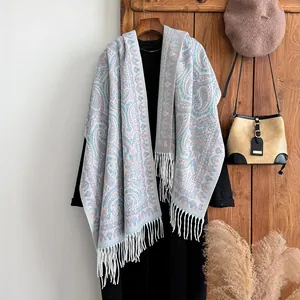 Détail du châle à motif paisley avec franges douces sur des vêtements noirs d'automne