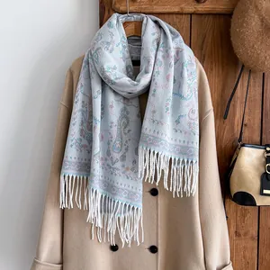 Détail d'un châle cachemire bleu clair à motif paisley et franges sur un manteau beige