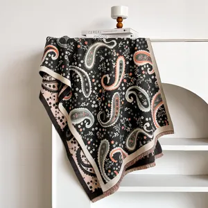 Close-up of deep grey paisley shawl featuring fine tassels and soft knitted texture