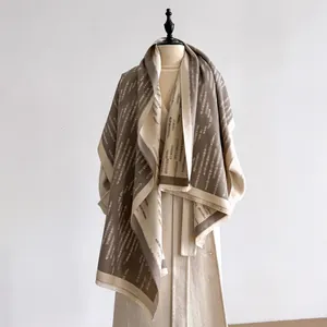 Dettaglio di una maxi sciarpa con motivo geometrico a righe nei colori marrone e beige